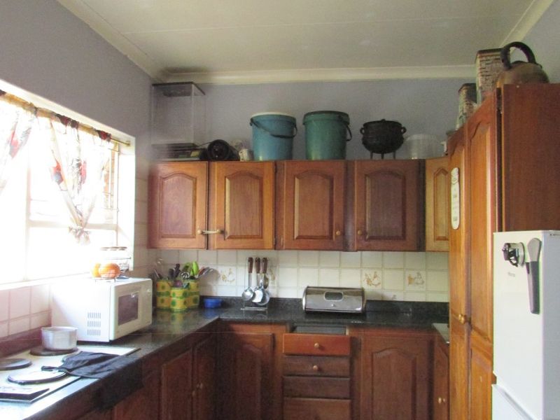 A functional kitchen featuring traditional wooden cabinetry, granite countertops, and tiled flooring, offering a dated aesthetic with potential for modern renovation.