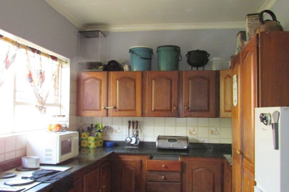 A functional kitchen featuring traditional wooden cabinetry, granite countertops, and tiled flooring, offering a dated aesthetic with potential for modern renovation.