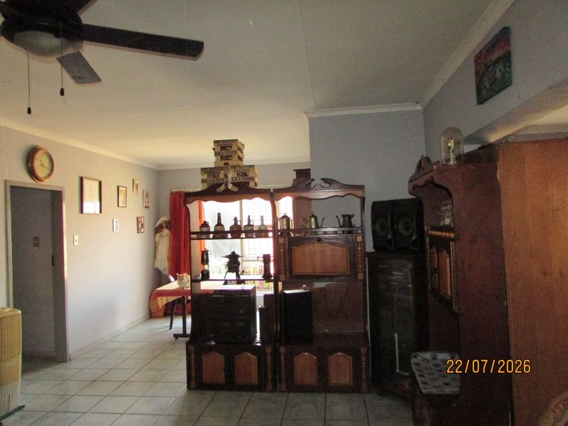 A living area featuring tiled flooring and a ceiling fan, offering a functional space with neutral wall finishes.