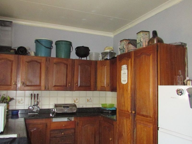 A dated kitchen featuring traditional wooden cabinetry, granite countertops, and a tiled backsplash, offering significant potential for a modern renovation.