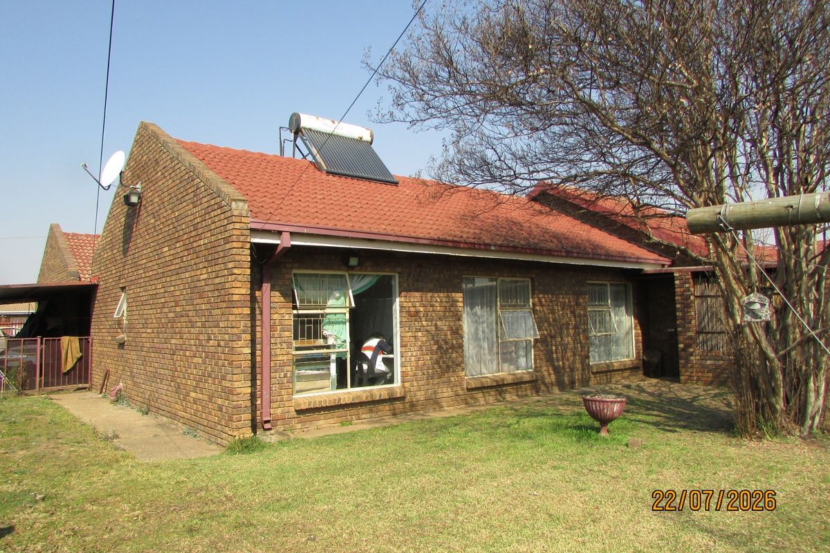 Rear view of a face brick house featuring a tiled roof and an installed solar water heating system.