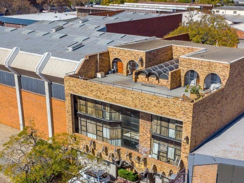 Aerial view of a multi-story commercial building featuring a brick facade, large windows, and a rooftop terrace area.