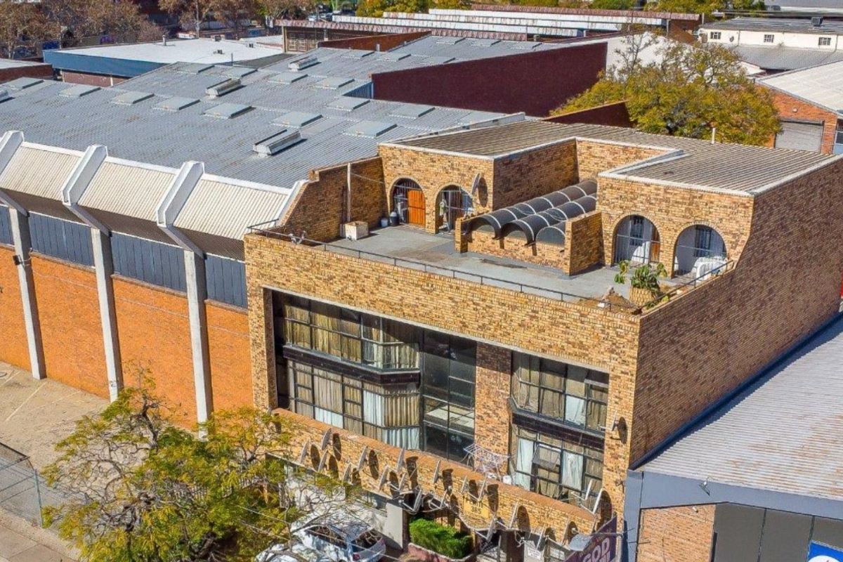 Aerial view of a multi-story commercial building featuring a brick facade, large windows, and a rooftop terrace area.