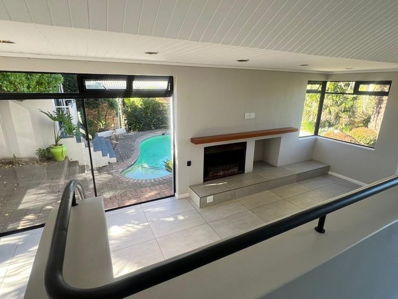 Spacious living area featuring tiled floors, a built-in fireplace, and large sliding doors providing direct access to the outdoor pool area.