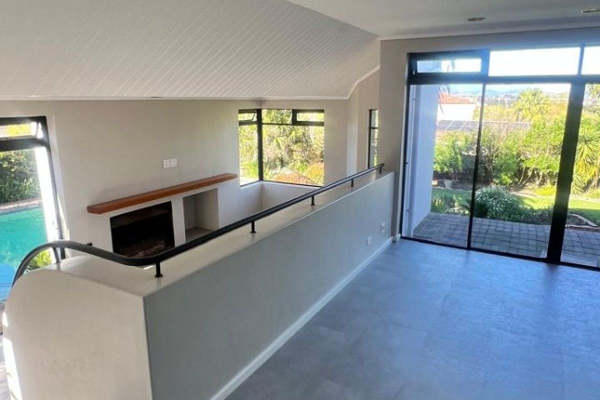 Spacious, light-filled living area featuring a modern fireplace, sleek tiled flooring, and large sliding glass doors opening to an outdoor view.