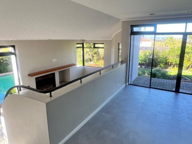 Spacious, light-filled living area featuring a modern fireplace, sleek tiled flooring, and large sliding glass doors opening to an outdoor view.