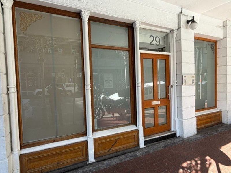 Front facade of a commercial office space featuring timber-framed display windows, a classic wooden entrance door, and decorative architectural detailing.
