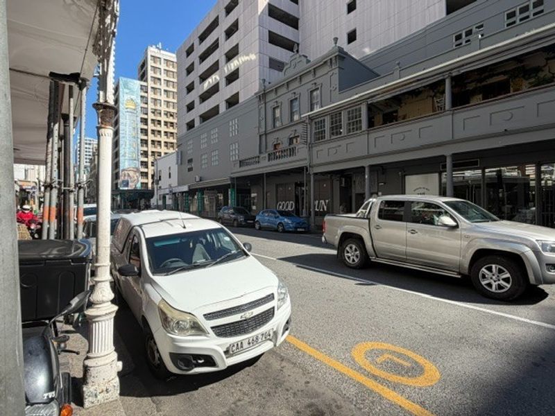 Street level view of a commercial office building facade featuring historic architectural details and a covered pedestrian walkway.