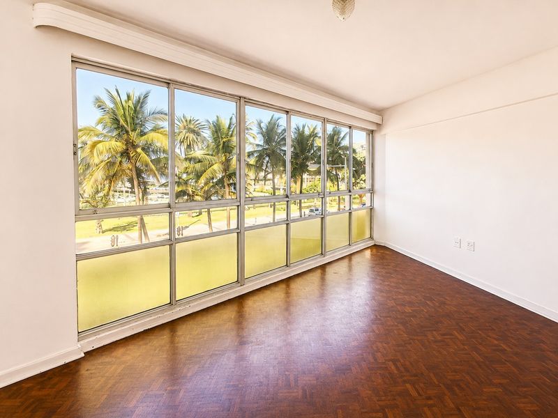 Bright and spacious living area featuring classic parquet flooring and expansive windows offering pleasant views of palm trees and the surrounding area.