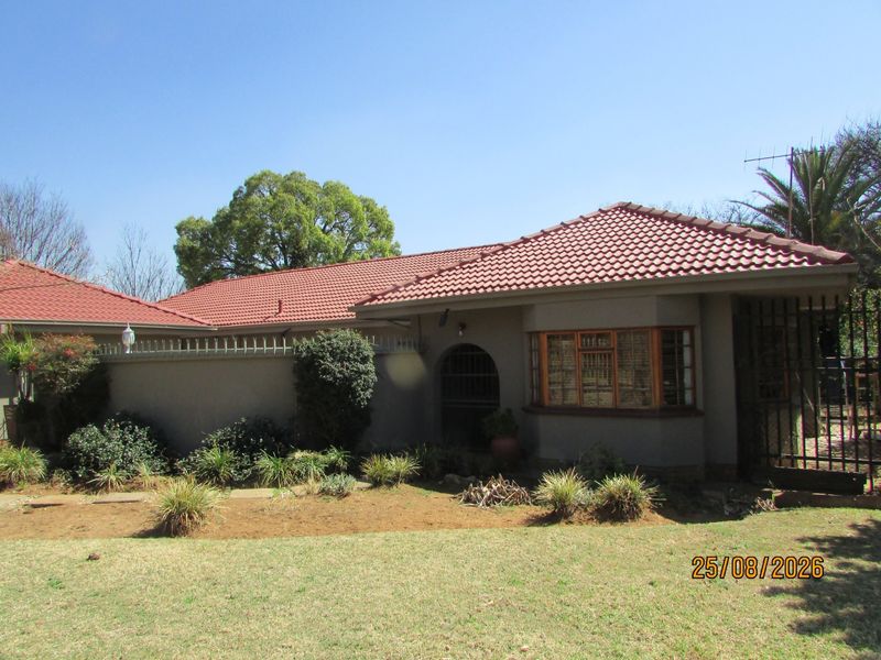 Front elevation of a single-story house featuring a tiled roof, bay window, and secure boundary wall with integrated security spikes.