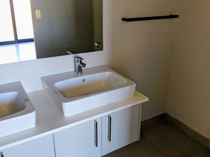 Modern bathroom featuring a double vanity with ceramic basins, chrome fixtures, and clean cabinetry, providing a functional and contemporary space.