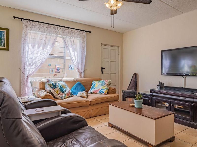 A comfortable living room featuring tiled flooring, a ceiling fan, and natural light from the window.
