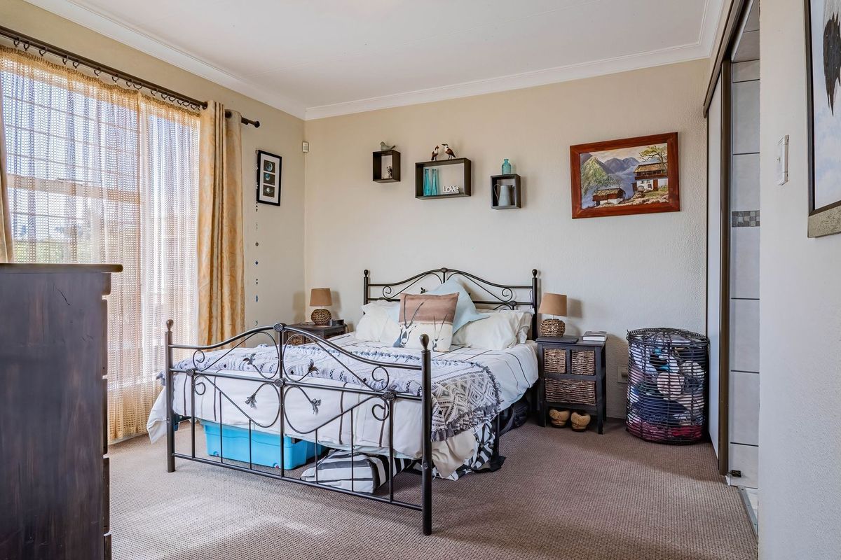A carpeted bedroom featuring a built-in sliding door wardrobe and neutral wall finishes, offering a comfortable and functional living space.
