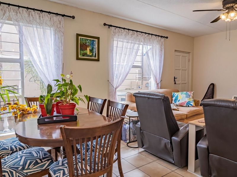 Open-plan living and dining area featuring tiled flooring, ceiling fan, and large windows with security bars, providing a functional and well-lit space.