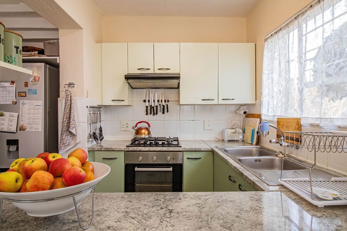 A functional kitchen featuring granite countertops, built-in cabinetry, a gas hob, and a stainless steel double sink with a window view.