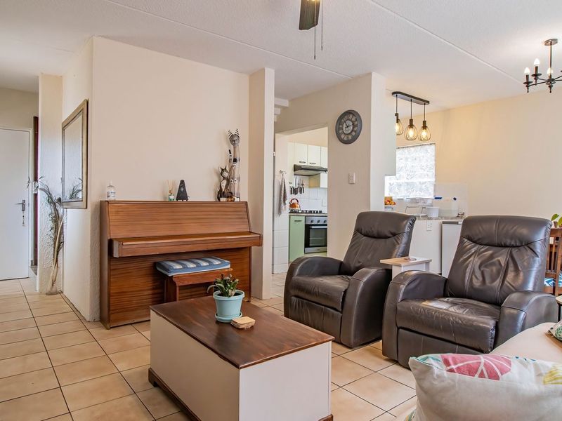 Open-plan living area featuring tiled flooring, integrated kitchen with built-in appliances, and a connected dining space, offering a functional and versatile layout.