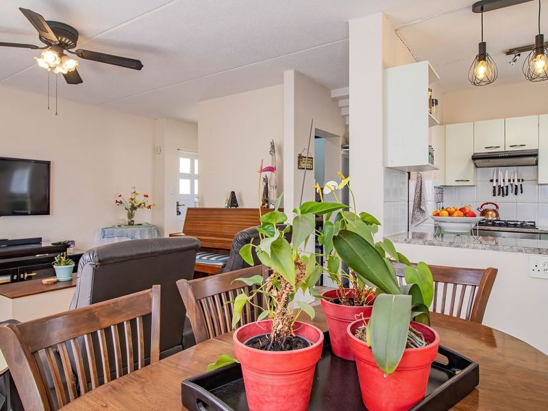 Open-plan living and kitchen area featuring tiled backsplash, granite countertops, and modern pendant lighting, creating a functional and connected living space.