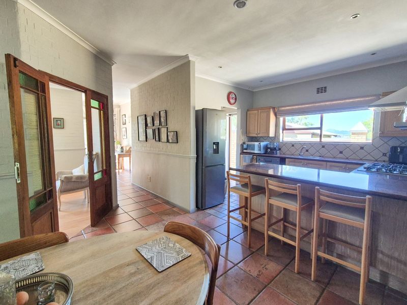 Open plan kitchen and dining area featuring terracotta flooring, granite countertops, wooden cabinetry, and direct access to adjacent living spaces through timber framed doors.