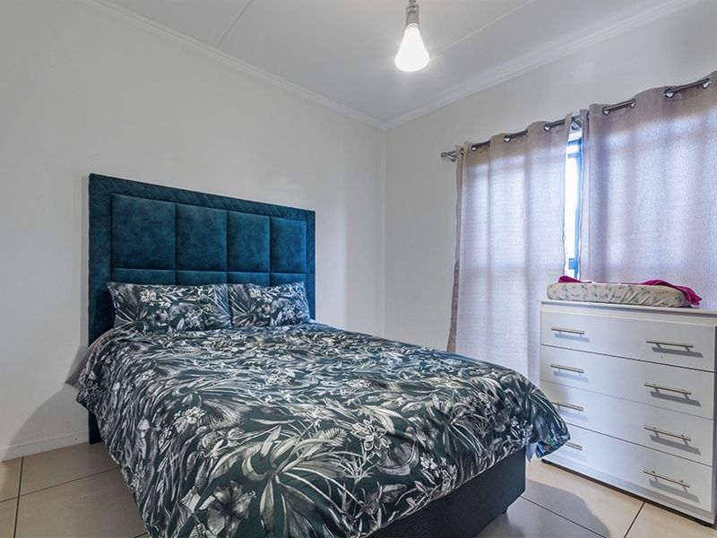 A functional bedroom featuring tiled flooring and a window with installed curtain rods, providing a neutral base for personalization.