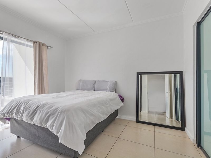 A bright bedroom featuring tiled flooring and a sliding glass door providing access to an outdoor area.