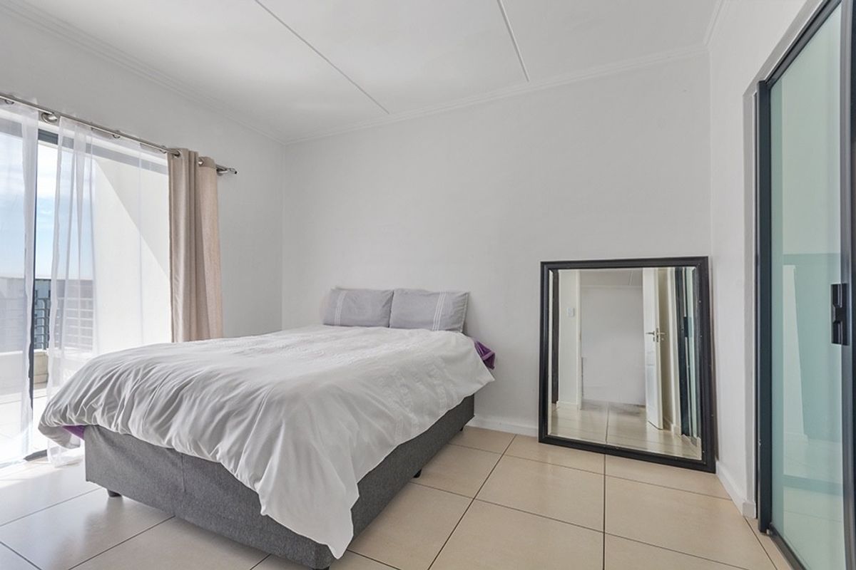 A bright bedroom featuring tiled flooring and a sliding glass door providing access to an outdoor area.