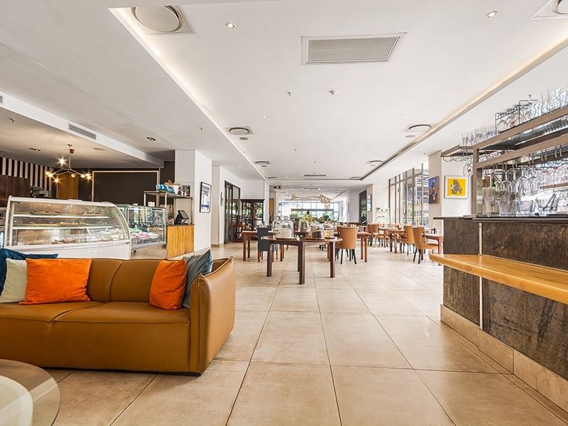 Spacious open-plan commercial or residential area featuring tiled flooring, recessed lighting, ducted air conditioning, and a built-in bar counter.
