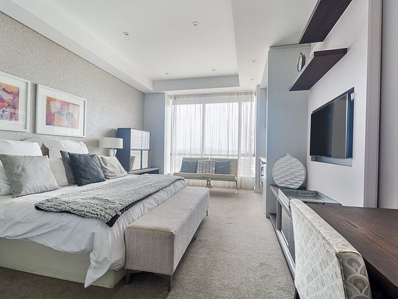 A well-maintained bedroom featuring recessed ceiling lighting, built-in shelving, and a large window providing natural light.