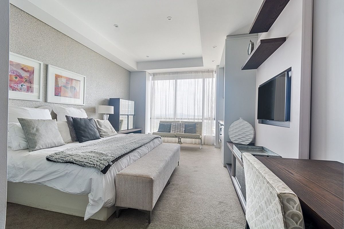 A well-maintained bedroom featuring recessed ceiling lighting, built-in shelving, and a large window providing natural light.
