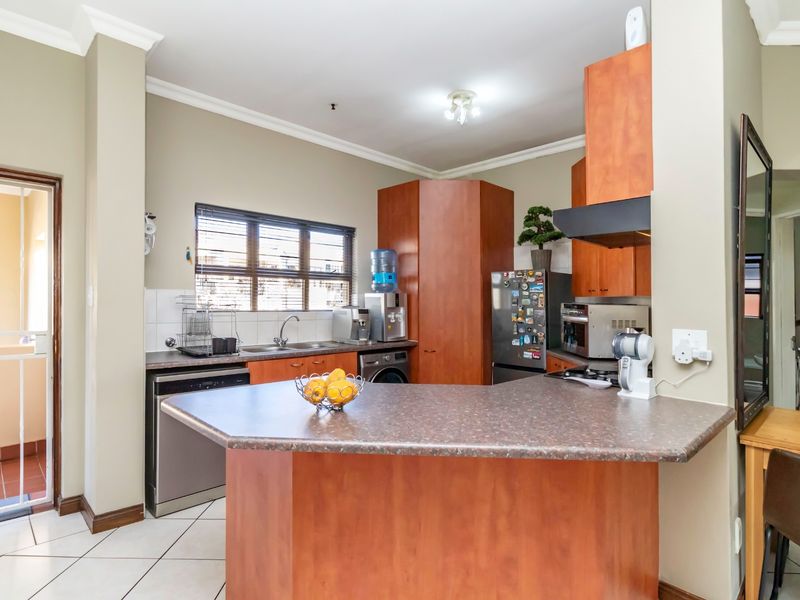 Functional kitchen featuring laminate cabinetry, ample countertop space, tiled flooring, and direct access to an outdoor balcony area.