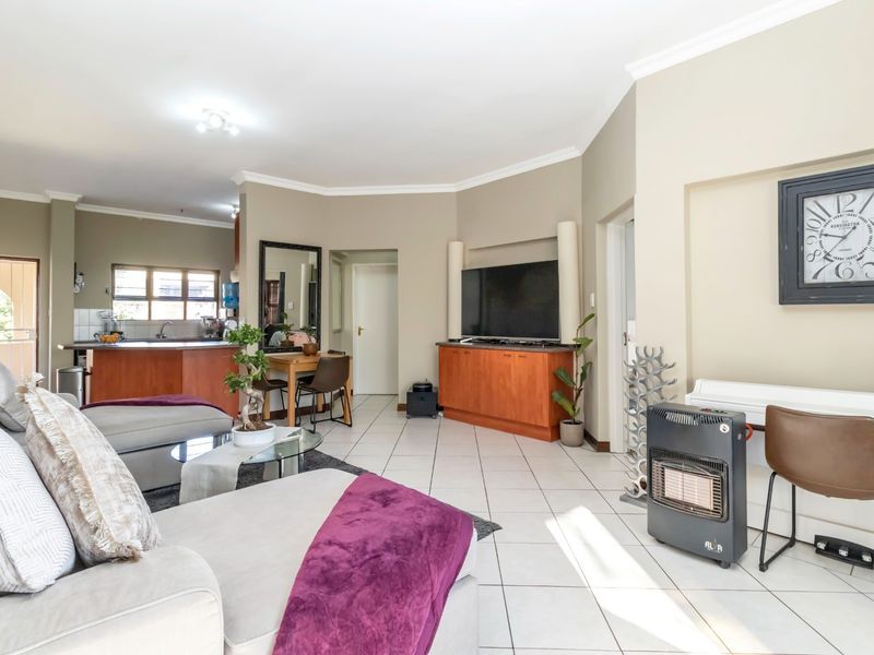 Spacious open-plan living area featuring tiled floors, integrated kitchen cabinetry, and a functional layout connecting the lounge and kitchen spaces.