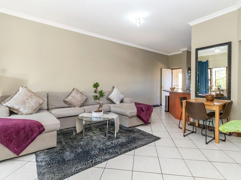 Open plan living and dining area featuring tiled flooring and a breakfast counter, providing a functional and connected layout.