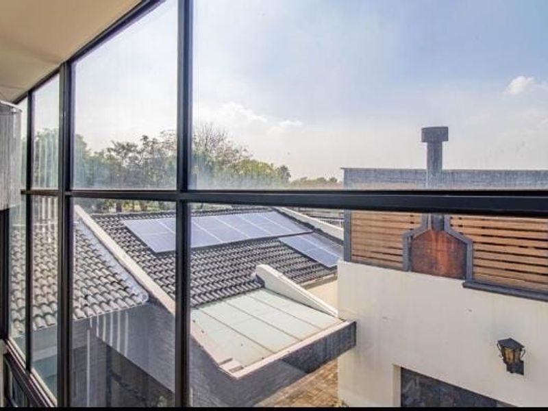 An elevated view through a large floor-to-ceiling window looking out over neighboring rooftops equipped with solar panels.