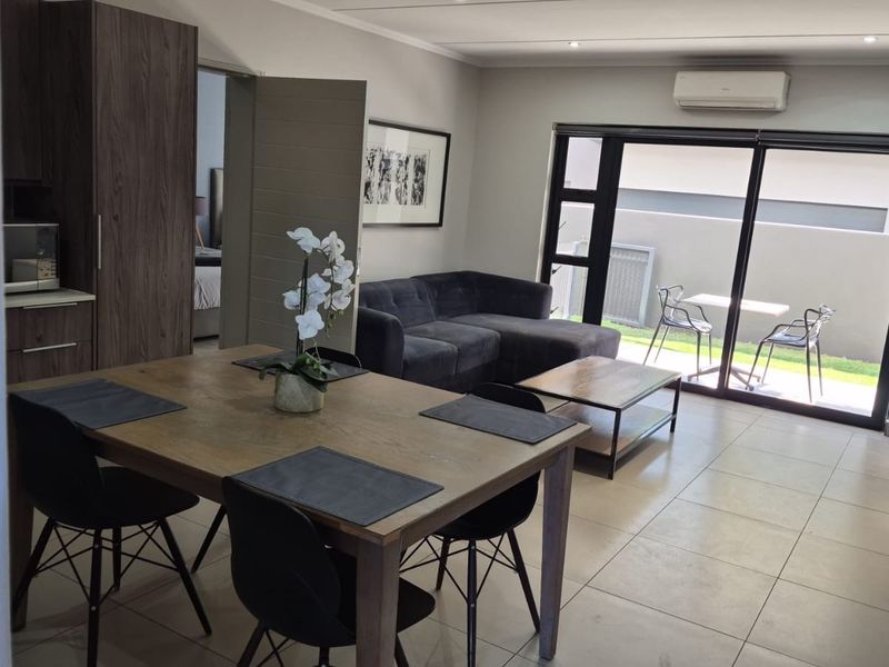 Modern open-plan living and dining area featuring tiled floors, built-in cabinetry, and large sliding glass doors leading to an outdoor patio space.