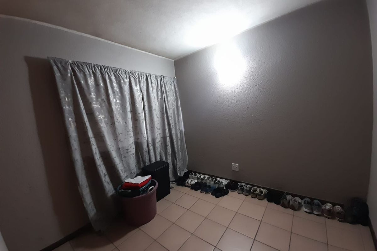A simple, vacant bedroom featuring tiled flooring and neutral wall tones, offering a blank canvas for personalization.