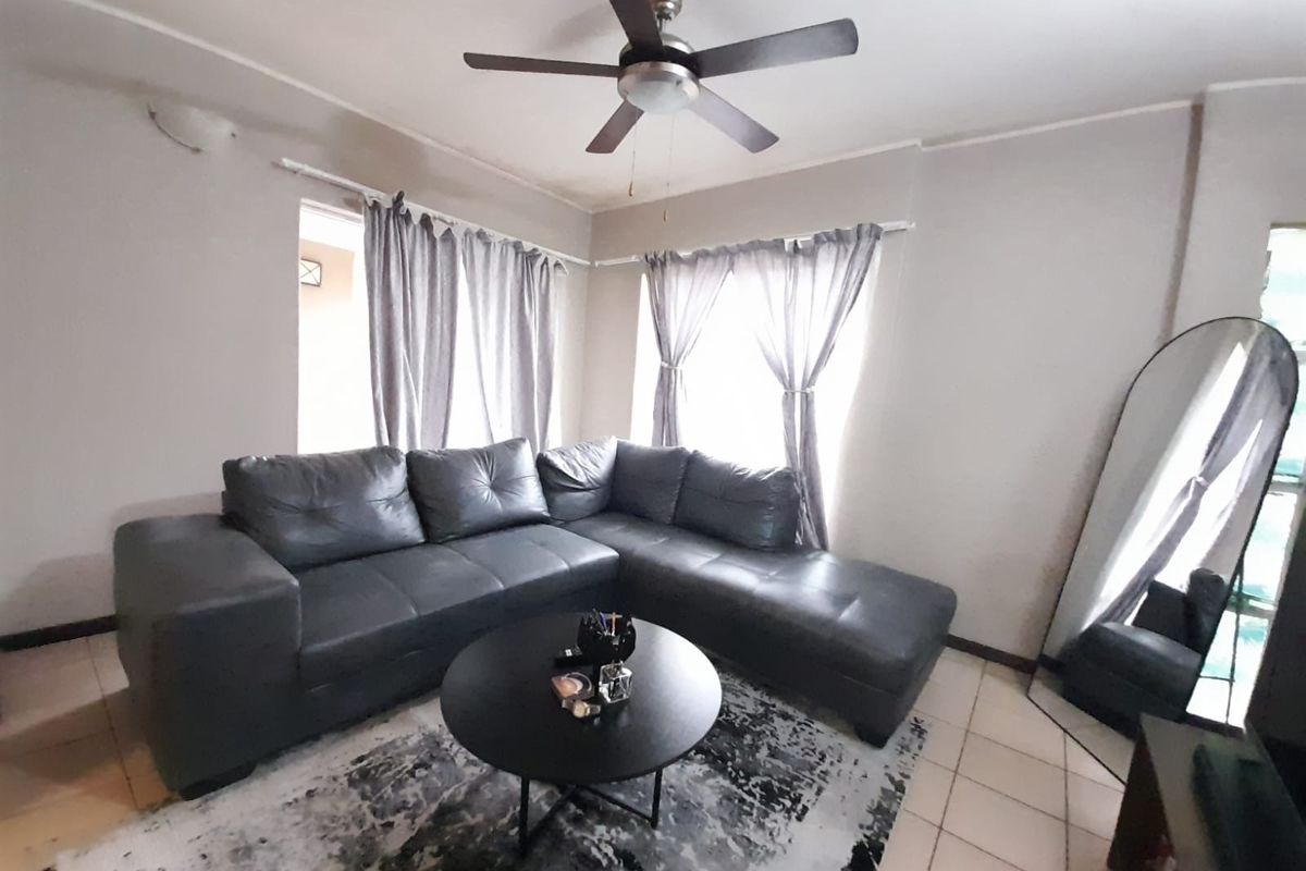 A living room featuring tiled flooring and a ceiling fan, providing a functional and neutral space for relaxation.