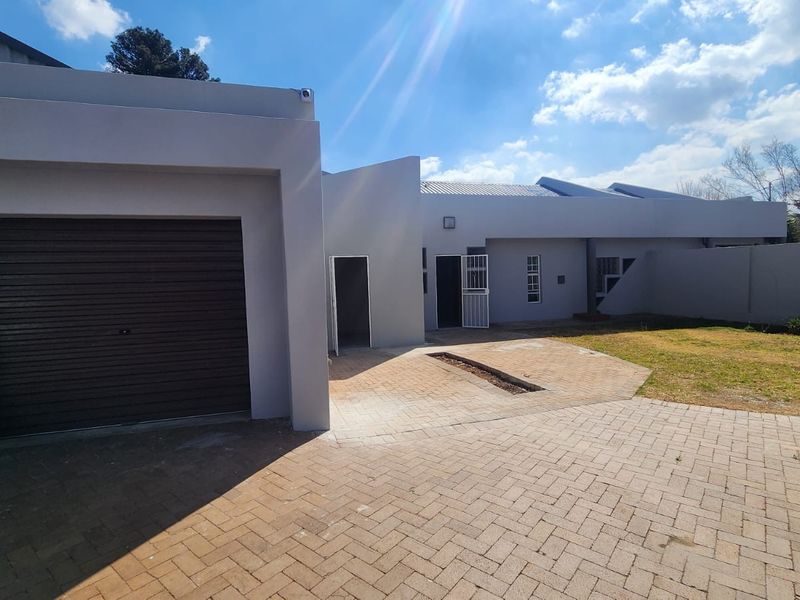 Front exterior view of the property featuring a paved driveway, a single roller garage door, and a secure entrance area.