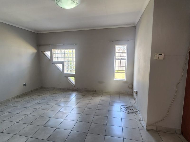 An empty bedroom featuring tiled flooring, a built-in cupboard, and unique glass block windows, providing a neutral canvas for personalization.