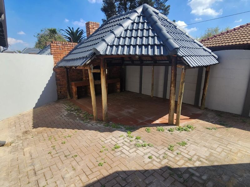 Outdoor entertainment area featuring a covered gazebo structure with a built-in brick braai and paved patio space.