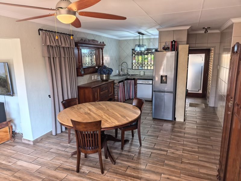 Open-plan kitchen and dining area featuring tiled flooring, built-in cabinetry, and a ceiling fan, offering a functional layout for daily living.