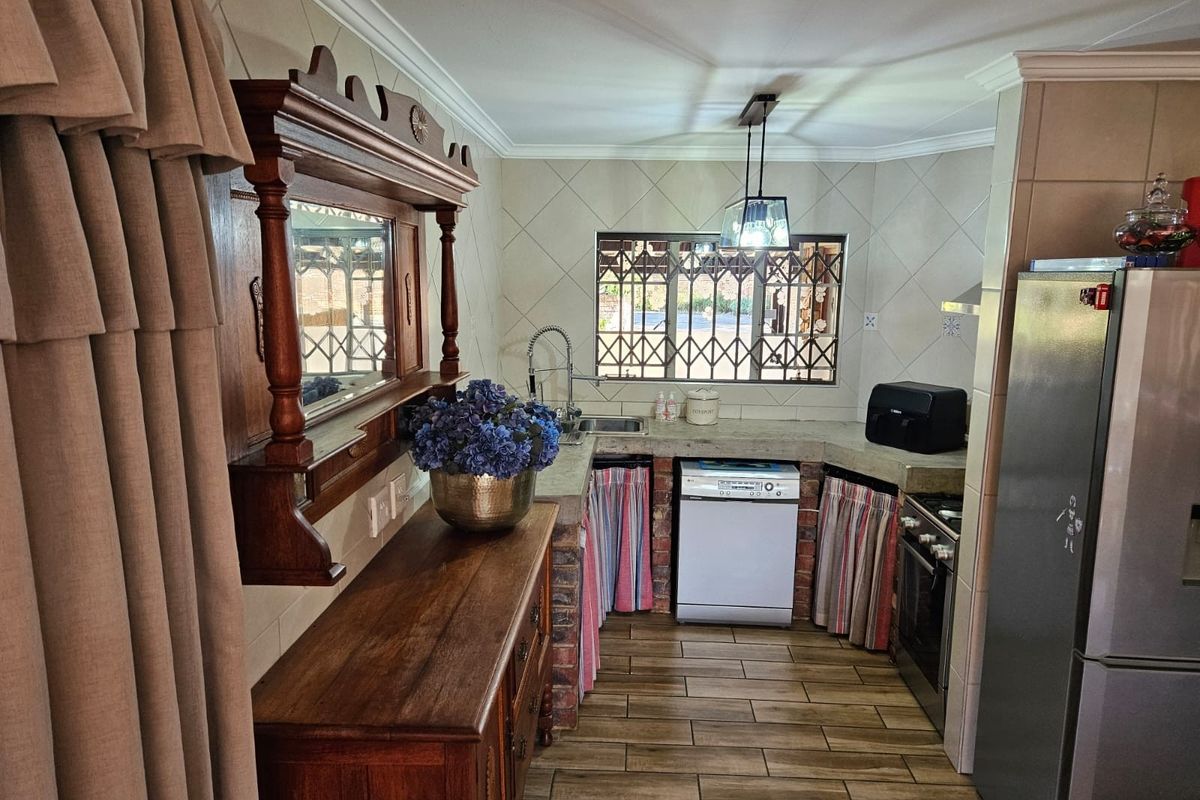 A functional kitchen featuring tiled flooring, a built-in oven with extractor, and a tiled backsplash, with a rustic brick-based cabinetry design.