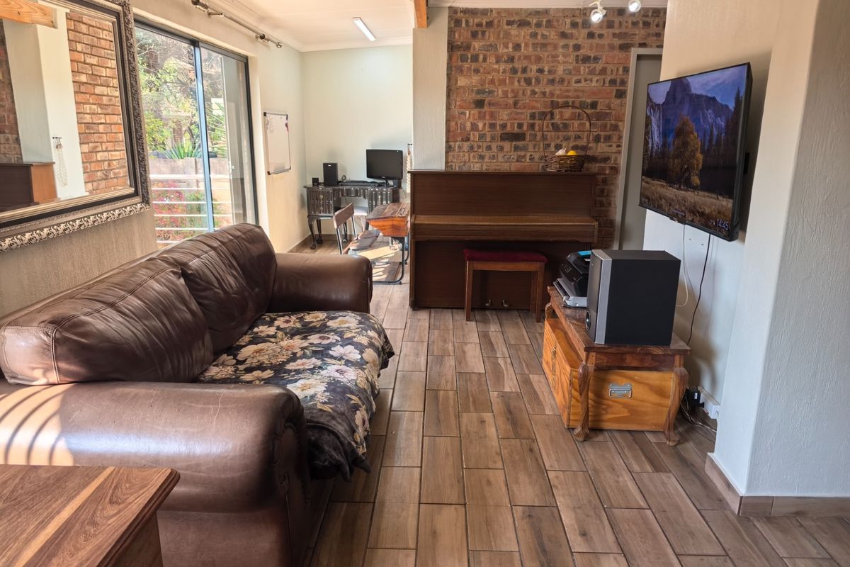 A living room featuring an exposed brick wall, tiled flooring, and a sliding glass door providing natural light and access to the exterior.