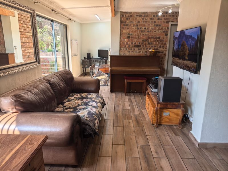 A living room featuring an exposed brick wall, tiled flooring, and a sliding glass door providing natural light and access to the exterior.
