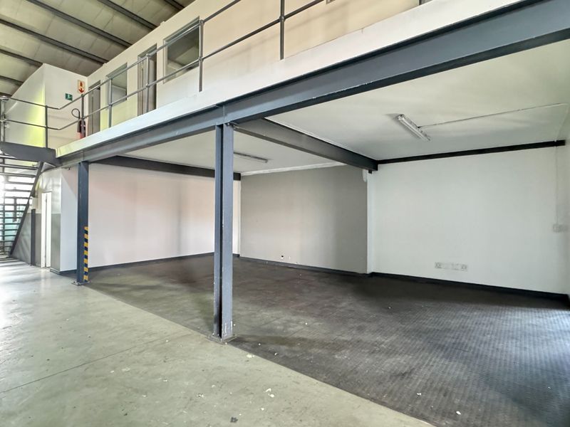 Spacious industrial utility area featuring a steel mezzanine level, staircase, and open-plan floor space suitable for storage, workshop, or office conversion.