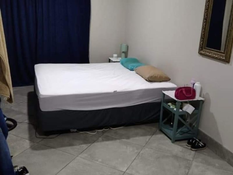 A simple bedroom featuring neutral wall paint and large format floor tiles.