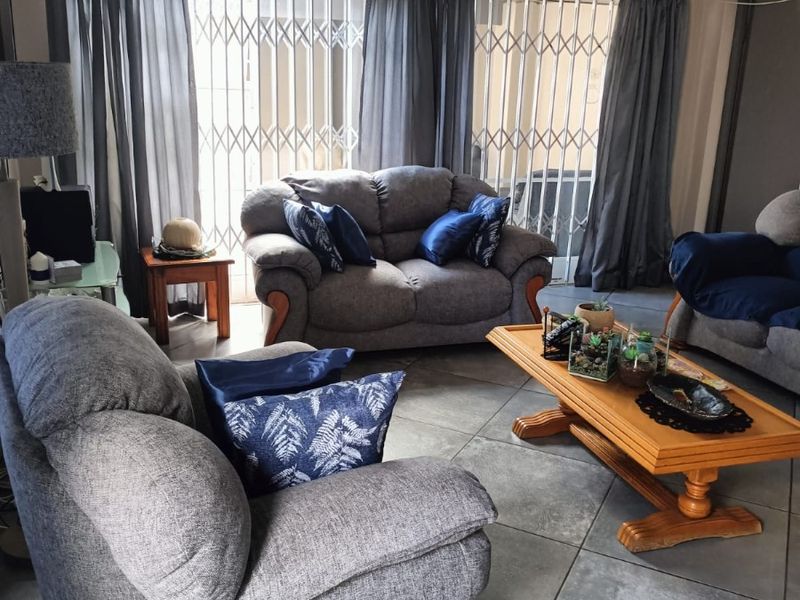 A living room featuring large format floor tiles, a sliding glass door with security gate, and neutral wall finishes.