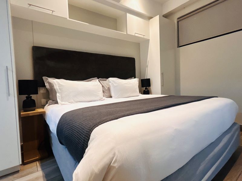 A well-maintained bedroom featuring integrated overhead cabinetry and built-in storage units, providing efficient use of space with modern laminate flooring.