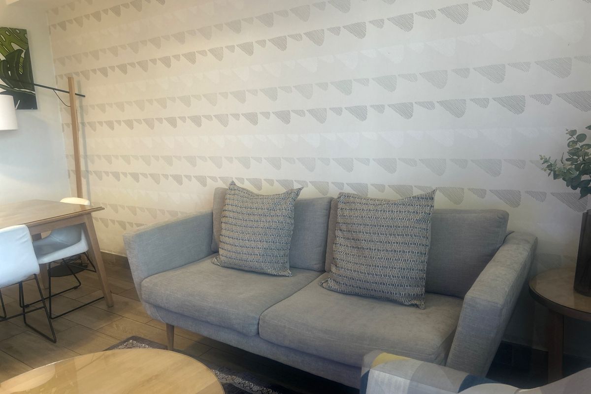 A cozy living room area featuring decorative patterned wallpaper and neutral tiled flooring, creating a comfortable and inviting atmosphere.