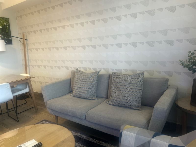 A cozy living room area featuring decorative patterned wallpaper and neutral tiled flooring, creating a comfortable and inviting atmosphere.