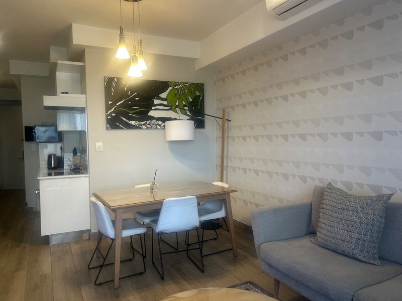 Open-plan living and dining area featuring modern cabinetry, integrated kitchen appliances, split-system air conditioning, and neutral finishes throughout.