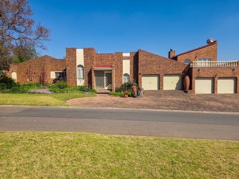 A well-maintained face-brick family home featuring a triple garage, paved driveway, and an upper-level balcony, set on a landscaped residential lot.